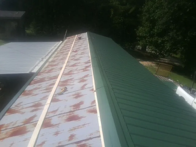 Old rusted panels beside newly installed green metal roofing — Wind Damage Roof Repair by Roofing Brothers in Sullivan