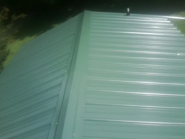 New green metal panels meeting at the ridge of a roof — Flat Roof Repair work by our crew in Sullivan