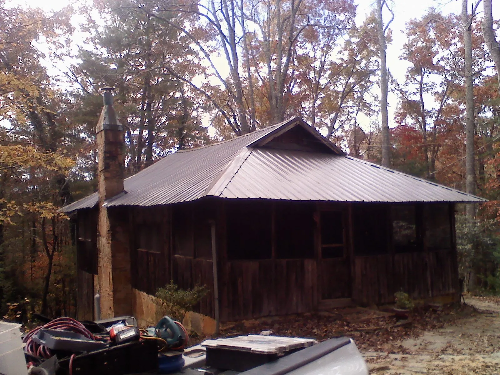 Brown metal hip roof on an old cabin with a stone chimney in Sullivan