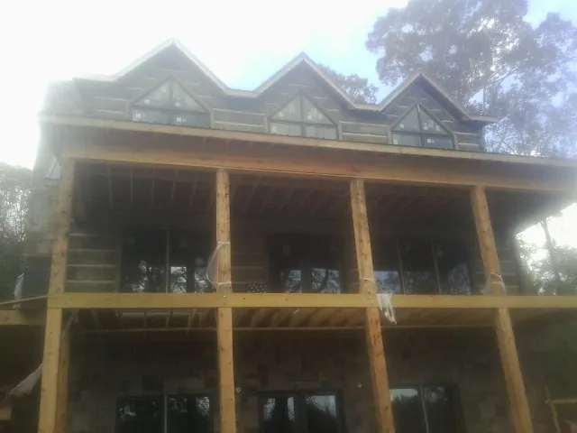 Dormers and porch framing on a large log home under construction — Roof Coating work by our crew in Sullivan